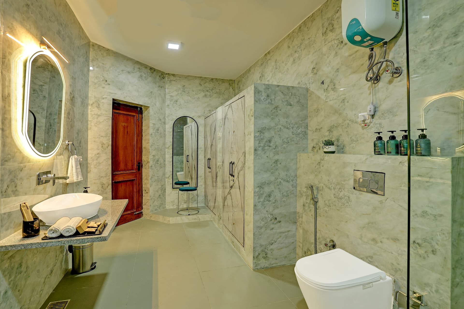 Ensuite bathroom in grey-green marble with lit mirror and glass shower