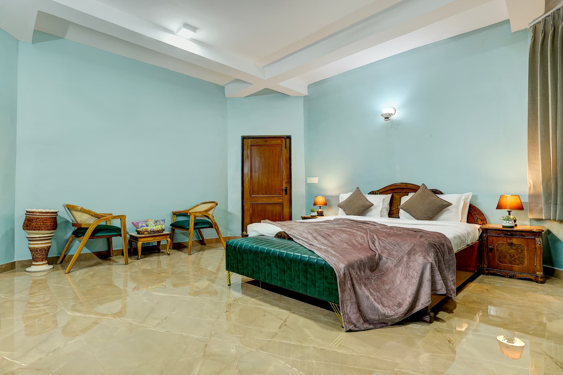 Mint green bedroom with carved wooden bed and cane lounge chairs