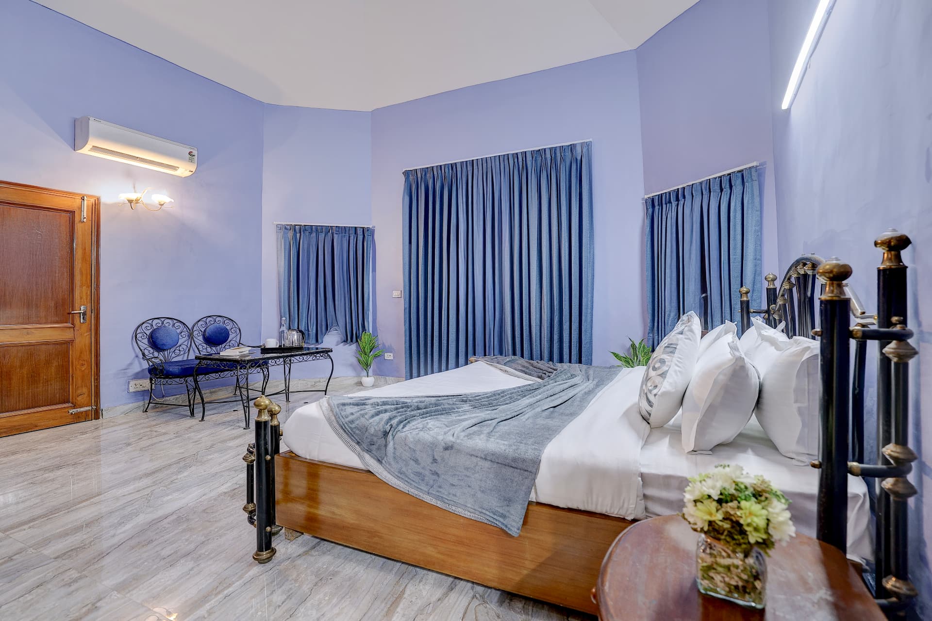 Periwinkle blue bedroom with brass and wood bed and blue curtains