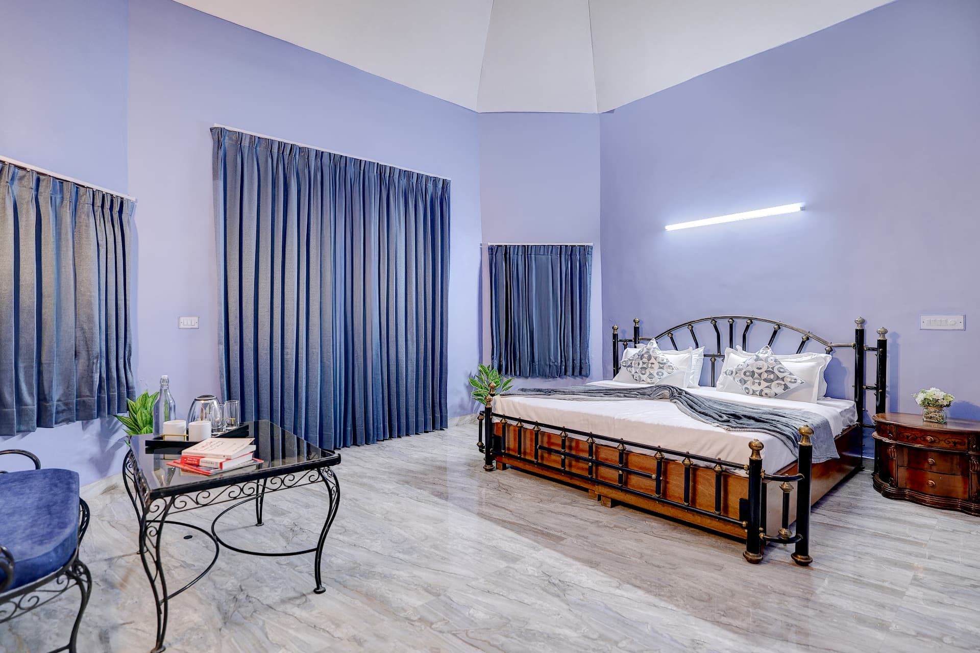 Periwinkle bedroom with wrought-iron table and tall curtained windows